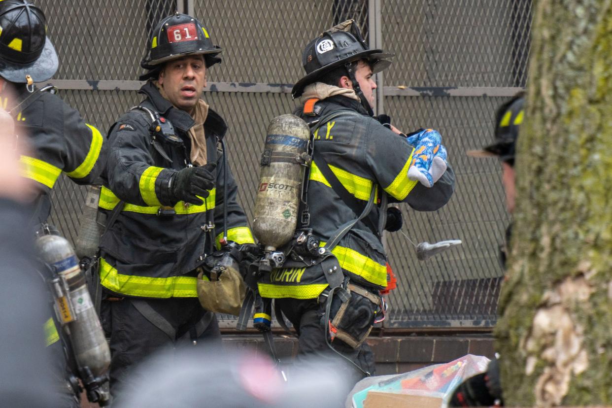 Firefighters rush to medics with a small child rescued from a burning building on Sunday, Jan. 9, 2022.