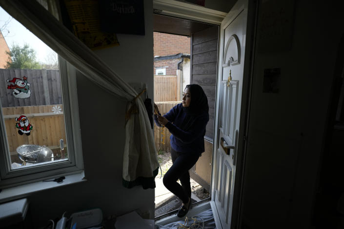 FILE - Bilqis Alam, an energy advisor from the South East London Community Energy co-operative (Selce), installs draught proofing rubber strips to the front door frame of the home of her client Tia Rutherford, in south east London, on March 22, 2022. As food costs and fuel bills soar, inflation is plundering people’s wallets, sparking a wave of protests and workers’ strikes around the world. (AP Photo/Matt Dunham)