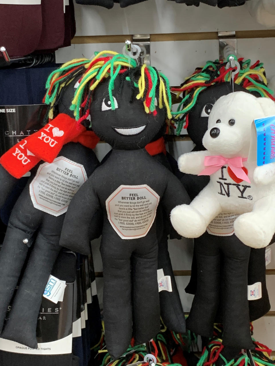 This undated photo provided by New Jersey state Assemblywoman Angela McKnight shows three "Feel Better Dolls" sharing the shelf with a stuffed animal bearing an "I Love New York" message at a One Dollar Zone store in Bayonne, N.J. The black rag "Feel Better" dolls that came with instructions to "find a wall" and slam the toy against it have been pulled from three stores after customers and the lawmaker said they were offensive. (Angela McKnight via AP)