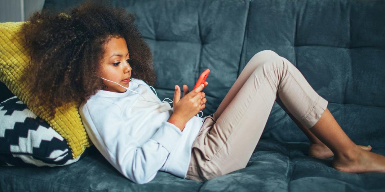 girl on couch with phone and headphones