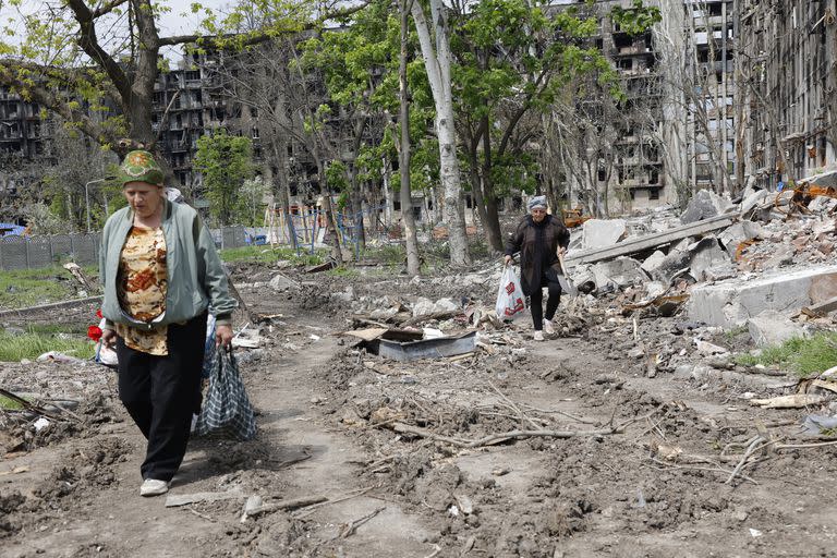 Las mujeres pasan frente a un edificio de apartamentos destruido en Mariupol