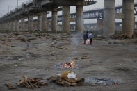 Relatives stand near the funeral pyre of their loved one who died due to COVID-19 at a cremation ground in Prayagraj, India, Saturday, May 8, 2021. (AP Photo/Rajesh Kumar Singh)