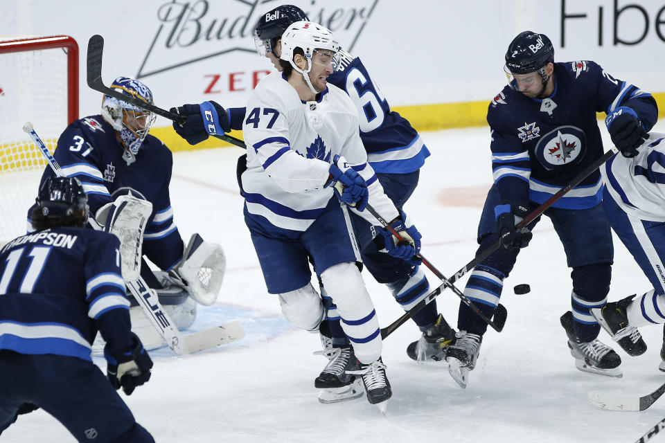 Toronto Maple Leafs' Pierre Engvall (47) attempts to tip the puck past Winnipeg Jets goaltender Connor Hellebuyck (37) during the second period of an NHL hockey game Wednesday, March 31, 2021, in Winnipeg, Manitoba. (John Woods/The Canadian Press via AP)