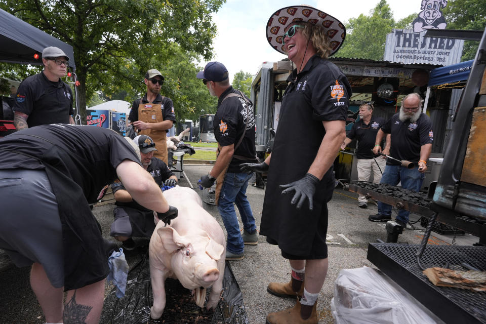 Brad Orrison, right, of the The Shed BBQ and Blues Joint team, prepares to cook a whole hog at the World Championship Barbecue Cooking Contest, Friday, May 17, 2024, in Memphis, Tenn. (AP Photo/George Walker IV)