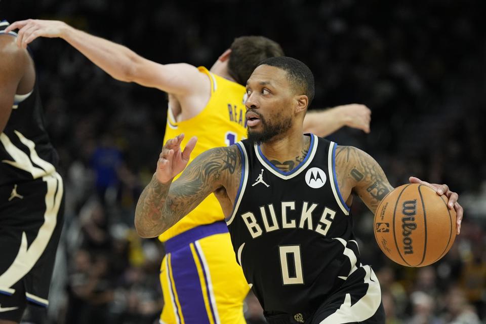 Milwaukee Bucks' Damian Lillard gets past Los Angeles Lakers' Austin Reaves during the second half of an NBA basketball game Tuesday, March 26, 2024, in Milwaukee. The Lakers won 128-124 in double overtime. (AP Photo/Morry Gash)