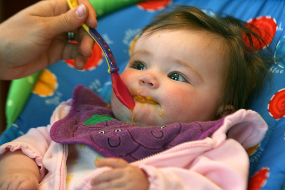 Baby being fed by food on spoon