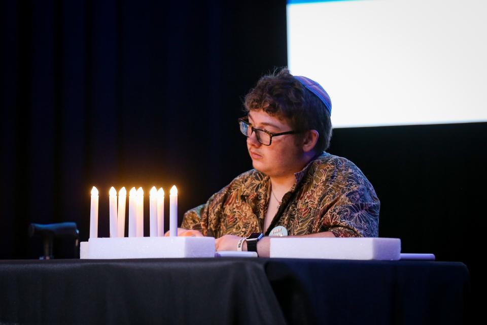 An individual "lights" candles in honor of transgender individuals who have lost their lives over the last year during the Transgender Day of Remembrance event at The Old Glass Place on Sunday, Nov. 20, 2022. The event included speakers, live music and an artist showcase.