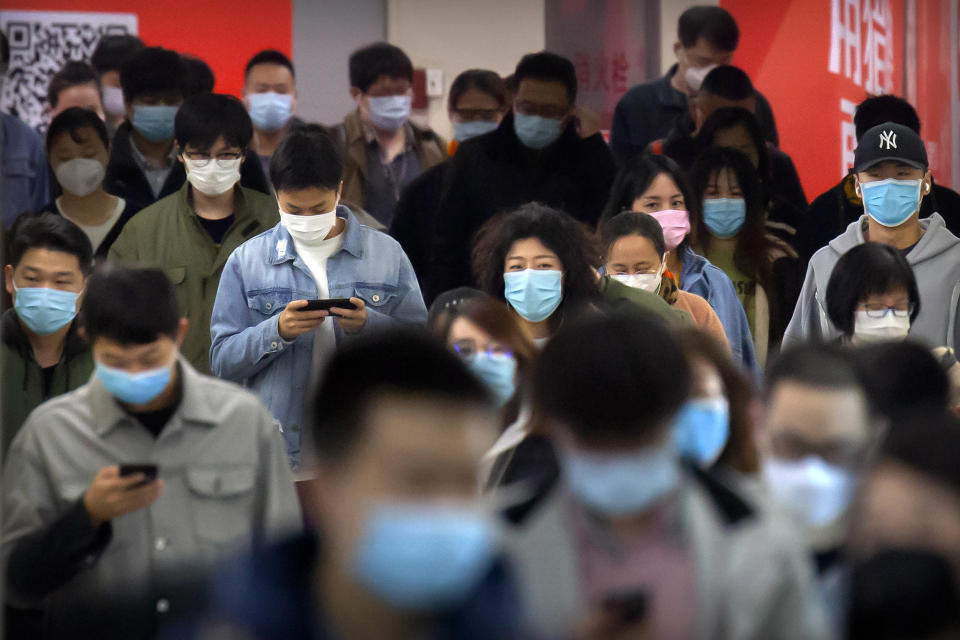 Image: Commuters wear face masks to protect against the spread of new coronavirus as they walk through a subway station in Beijing, (Mark Schiefelbein / AP)