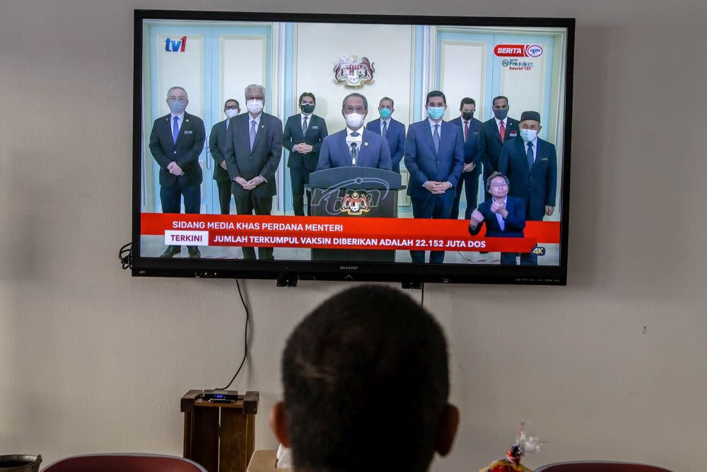 A man watches a live telecast of Prime Minister Tan Sri Muhyiddin Yassin's speech in Kuala Lumpur August 4, 2021. — Picture by Firdaus Latif