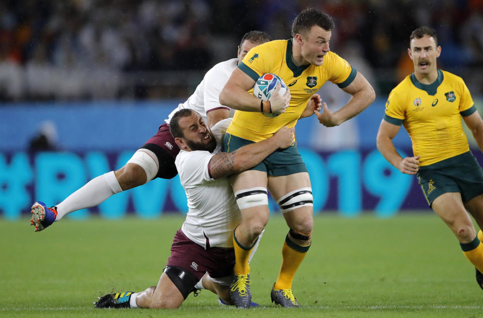 FILE - Australia's Jack Dempsey is tackled by Georgian defenders during the Rugby World Cup Pool D game at Shizuoka Stadium Ecopa between Australia and Georgia in Shizuoka, Japan, on Oct.11, 2019. A loophole that has allowed rugby players to more easily switch allegiances is helping reshape a sport that has previously tended to tie representative players to one country for life. (AP Photo/Christophe Ena, File)