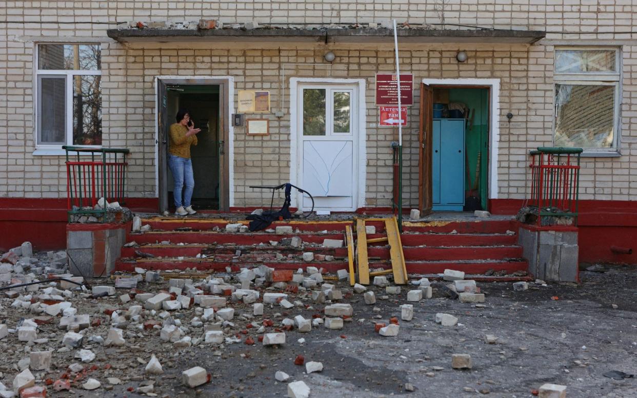 A woman stands at the entrance to a kindergarten building hit by shelling