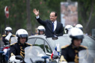 François Hollande, tout juste investi président de la République, salue la foule depuis sa voiture alors qu'il quitte le Palais de l'Elysée après la cérémonie d'investiture pour rejoindre l'Arc de Triomphe en remontant les Champs Elysées. AFP