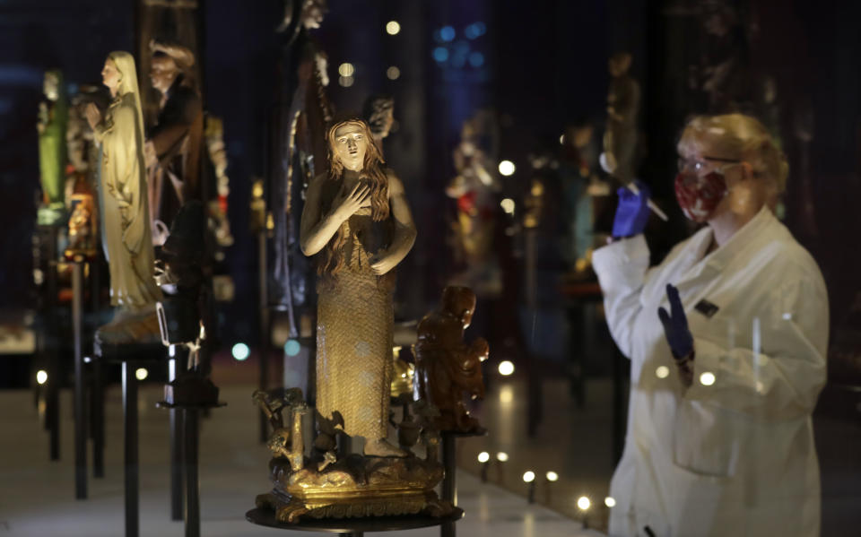Kate Perks, Senior Collections Care Conservator prepares a display of Deities and Saints, displayed at the Science Museum in London, Monday, May 17, 2021. The Science Museurm reopens to the public on Wednesday. (AP Photo/Kirsty Wigglesworth)