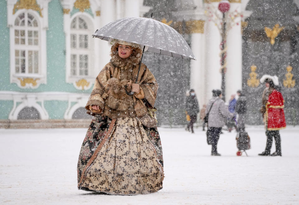 A street actress wearing 18th century styled clothes, walks in snowfall in central St. Petersburg, Russia, Sunday, Jan. 9, 2022. (AP Photo/Dmitri Lovetsky)