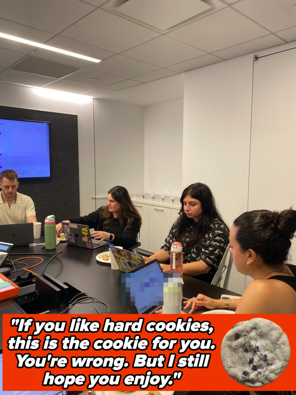 Group of four people working at a conference table, each with a laptop and a plate of cookies on the table.