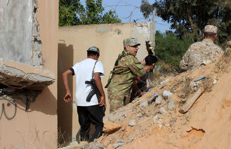 Members of the Libyan internationally recognised government forces look out from behind a wall at Khallat Farjan area in Tripoli, Libya April 20, 2019. REUTERS/Ayman al-Sahili