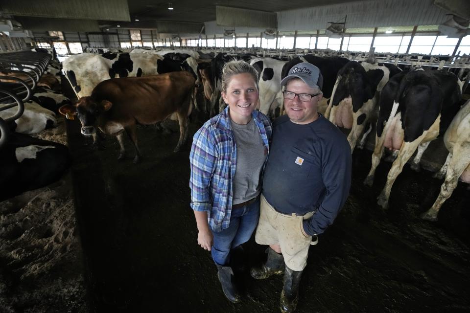 Dairy farmers Megan and Ted McAllister stand in the freestall barn on their farm, Monday, July 24, 2023, in New Vienna, Iowa. More intense summer heat resulting from emissions-driven climate change means animal heat stress that can result in billions of dollars in lost revenue for farmers and ranchers if not properly managed. The McAllister family installed new fans above the beds where their cows lie. (AP Photo/Charlie Neibergall)