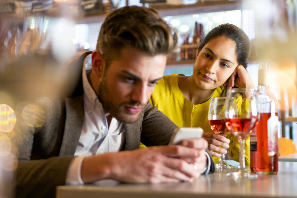 a man checking his phone on a date with a woman