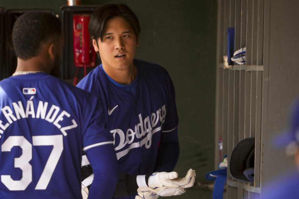 Los Angeles Dodgers designated hitter Shohei Ohtani, facing, talks with teammate Teoscar Hernández in the dugout during a spring training baseball game against the San Francisco Giants, Tuesday, March 12, 2024, in Phoenix. (AP Photo/Lindsey Wasson)