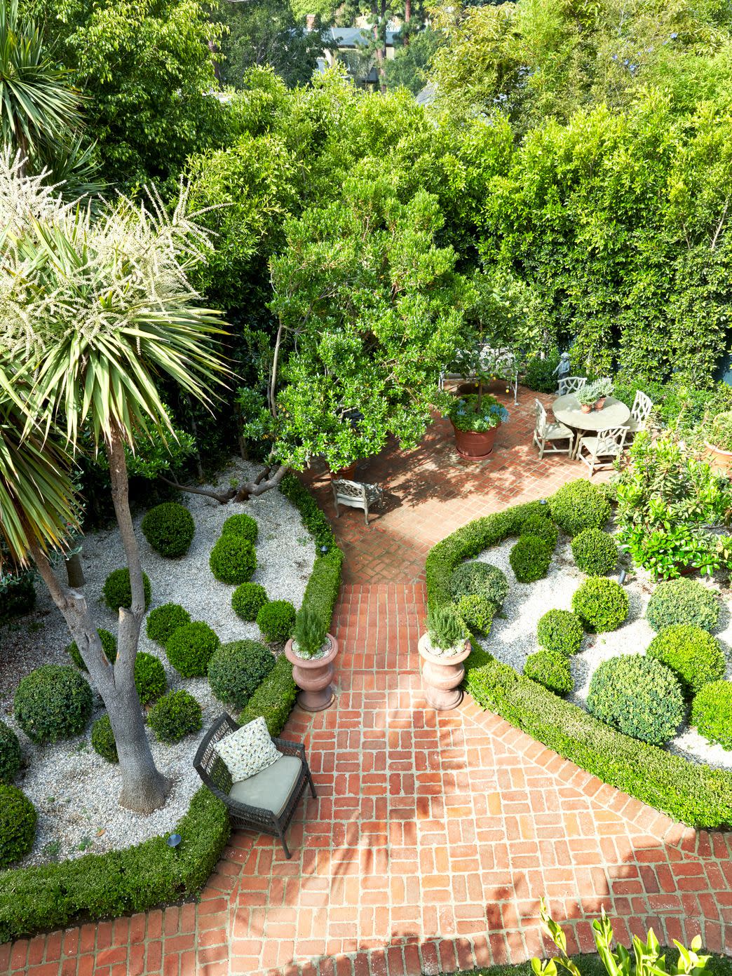 a brick patio with a brick path and a bench and plants