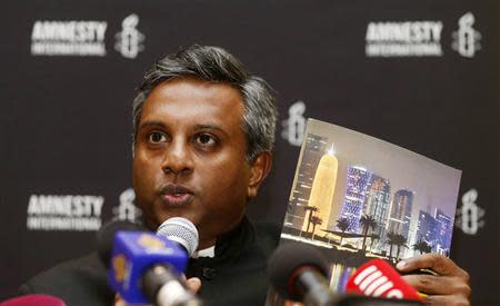 Amnesty International Secretary General Salil Shetty holds up a report titled "The Dark Side of Migration: Spotlight on Qatar’s construction sector ahead of the World Cup", during a news conference in Doha November 17, 2013. REUTERS/Mohammed Dabbous