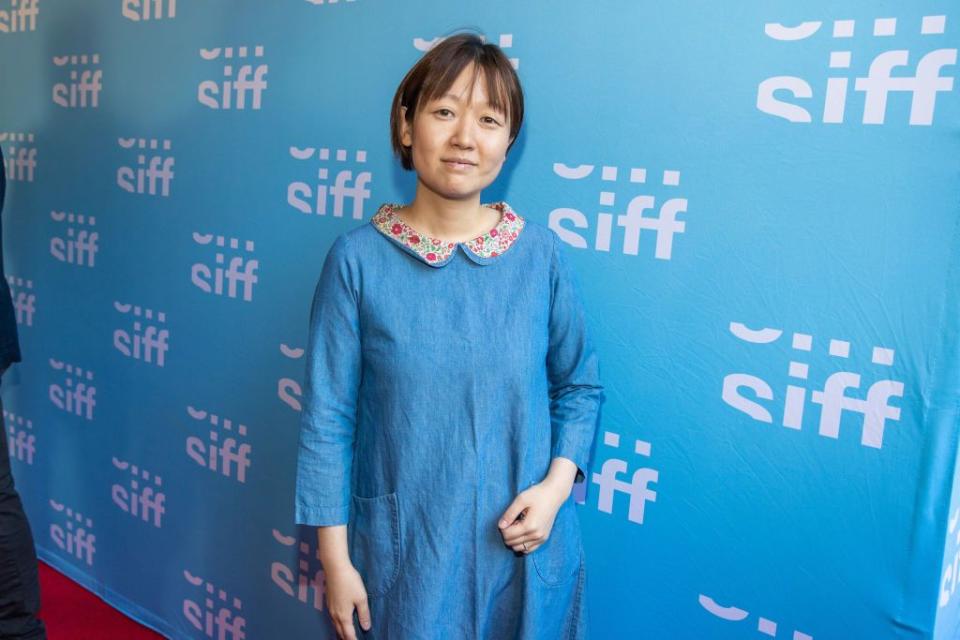 celine song wearing a blue dress and posing for a photo in front of a backdrop at the seattle international film festival