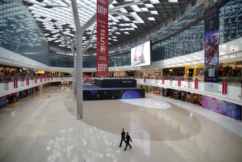 Security personnel wearing face masks walk inside a shopping mall in Beijing
