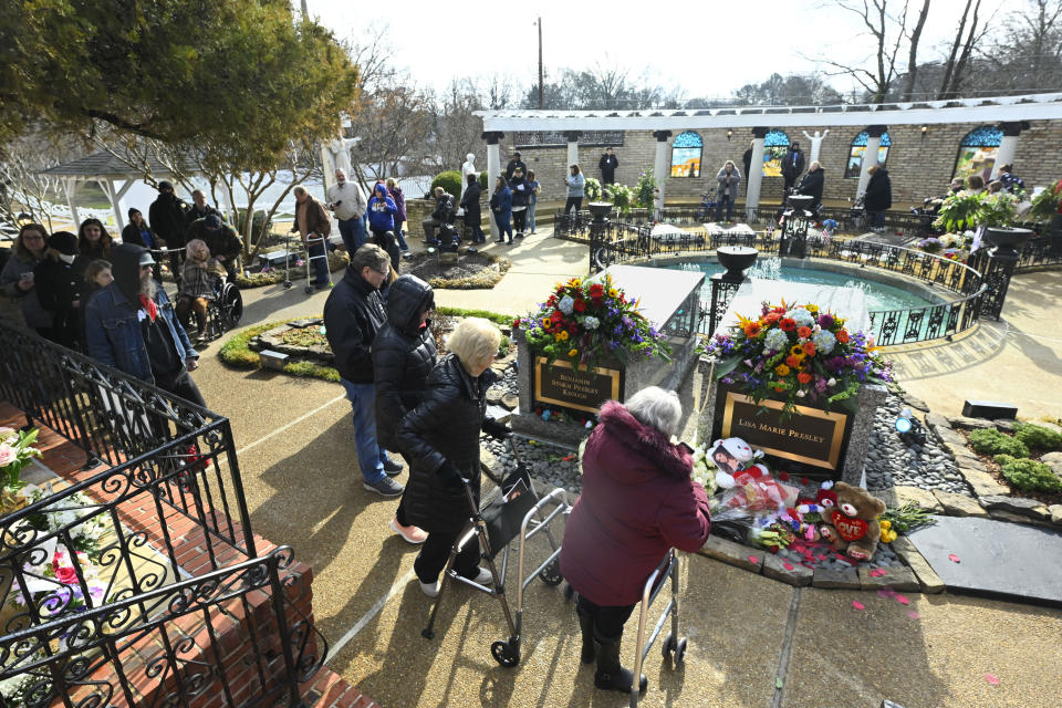 Visitors to Graceland look at the gravesite of Lisa Marie Presley and her son Benjamin Keough as the walk around the Meditation Gardens after a memorial service for Lisa Marie Sunday, Jan. 22, 2023, in Memphis, Tenn. She died Jan. 12 after being hospitalized for a medical emergency and was buried near her father Elvis Presley and his two parents. (AP Photo/John Amis)