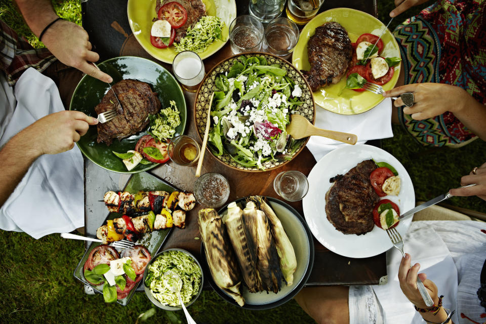 Overhead view of friends dining at table with food in backyard.