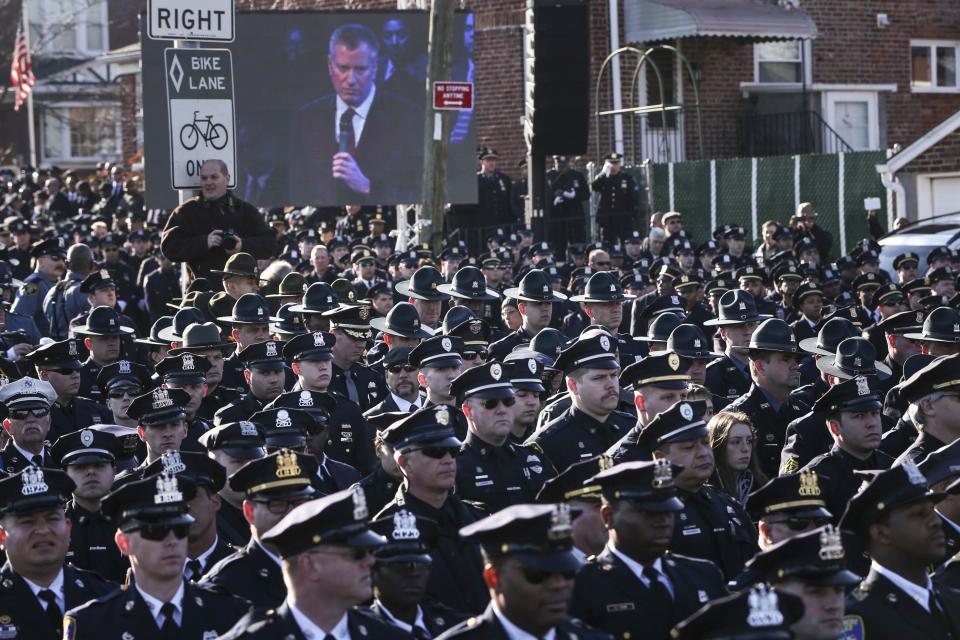 Law enforcement officers turn their backs on a live video monitor showing New York City Mayor Bill de Blasio as he speaks at the funeral of slain New York Police Department (NYPD) officer Rafael Ramos near Christ Tabernacle Church in the Queens borough of New York December 27, 2014. Tens of thousands of police and other mourners filled a New York City church and surrounding streets for the funeral on Saturday of one of two police officers ambushed by a gunman who said he was avenging the killing of unarmed black men by police. Singled out for their uniforms, the deaths of Rafael Ramos and his partner Wenjian Liu have become a rallying point for police and their supporters around the country, beleaguered by months of street rallies by protesters who say police practices are marked by racism. REUTERS/Shannon Stapleton (UNITED STATES - Tags: CIVIL UNREST POLITICS CRIME LAW TPX IMAGES OF THE DAY)