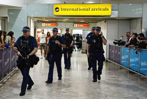 Armed police officers walk in front of the arrival gate at Heathrow airport, London, four days ahead of the London 2012 Olympic Games