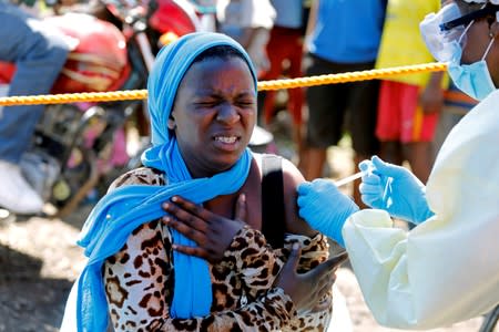 FILE PHOTO: A young woman reacts as a health worker injects her with the Ebola vaccine, in Goma