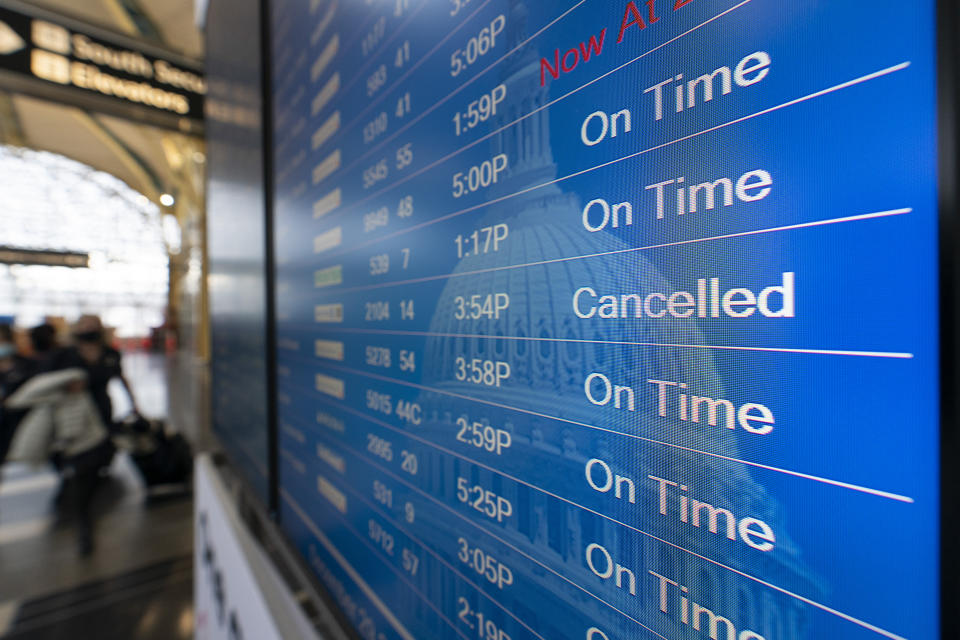 A flight shows cancelled on the departures board at Ronald Reagan Washington National Airport, Wednesday, Dec. 29, 2021, in Arlington, Va. Winter weather and crew members infected with COVID-19 have forced airlines to spike thousands of U.S. flights over the past week, complicating travel plans for many people during the busy holiday season. It’s not clear when travel will return to normal, but airlines say a recent move by U.S. public health officials should help get workers back sooner. (AP Photo/Alex Brandon)