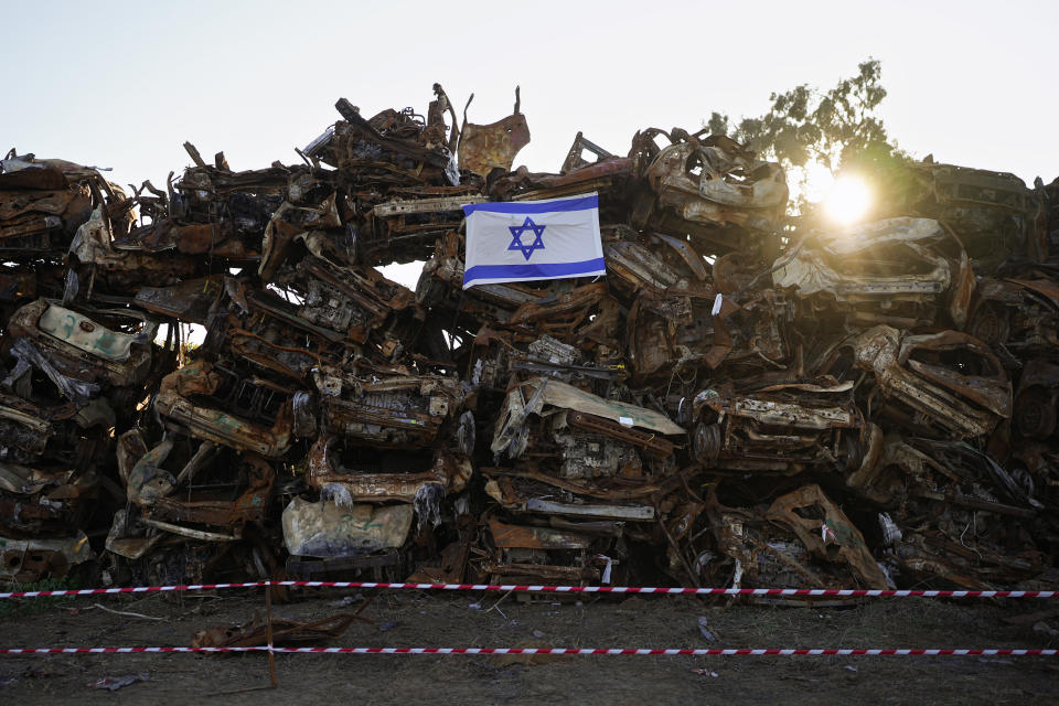 An Israeli flag is placed on a pile of charred vehicles burned in the bloody Oct. 7 cross-border attack by Hamas militants, outside the town of Netivot, southern Israel, Sunday, Jan.7, 2024. The vehicles were collected and placed in an area near the Gaza border after the attack, in which 1,200 people were killed and some 240 people were taken hostage.(AP Photo/Ohad Zwigenberg)