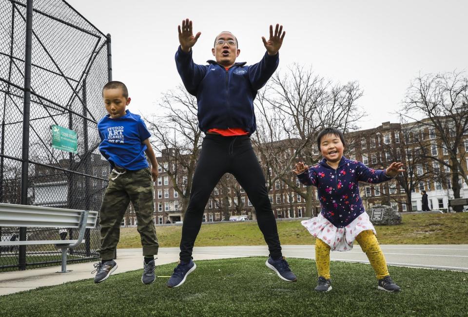 A father, son and young daughter jump while exercising outdoors together