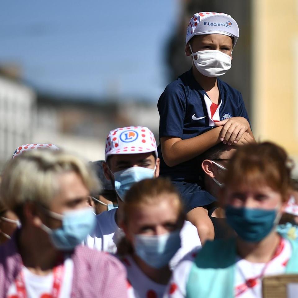 A child wearing face mask waits to see the riders before the start of the the 14th stage between Clermont-Ferrand and Lyon.