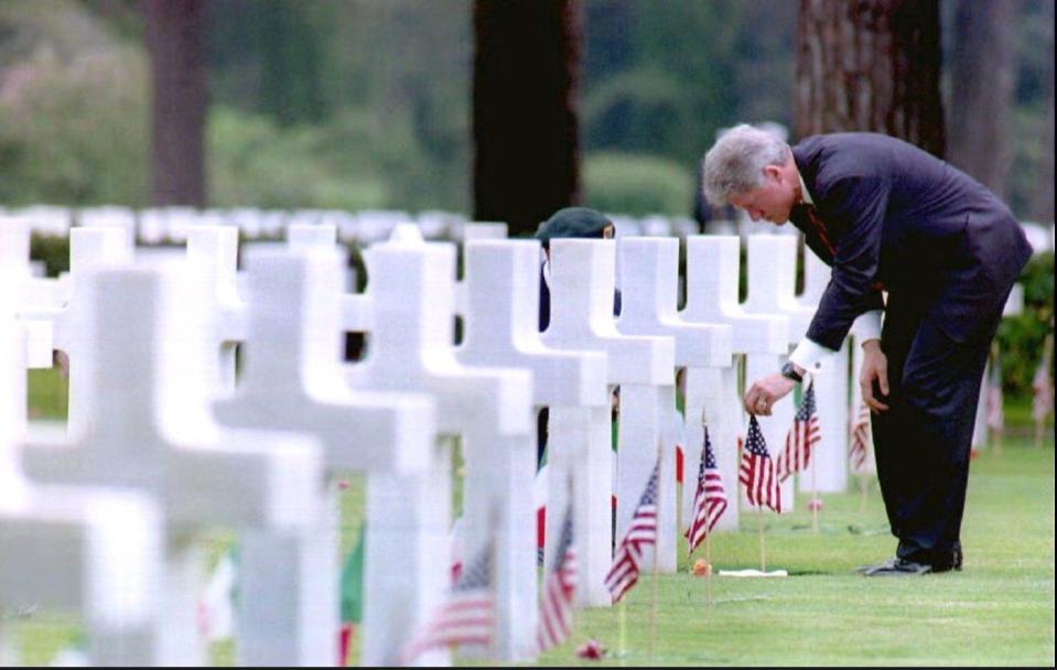 President Bill Clinton adjusts a U.S. flag at the grave of U.S. Army Lt. Robert Waugh in the Sicily-Rome American cemetery on June 3, 1994. The cemetery is the final resting place for 7,862 U.S. soldiers who died during the Italian campaign of WWII in 1943 and 1944.