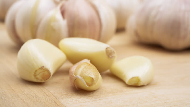Peeled garlic cloves beside whole bulbs 