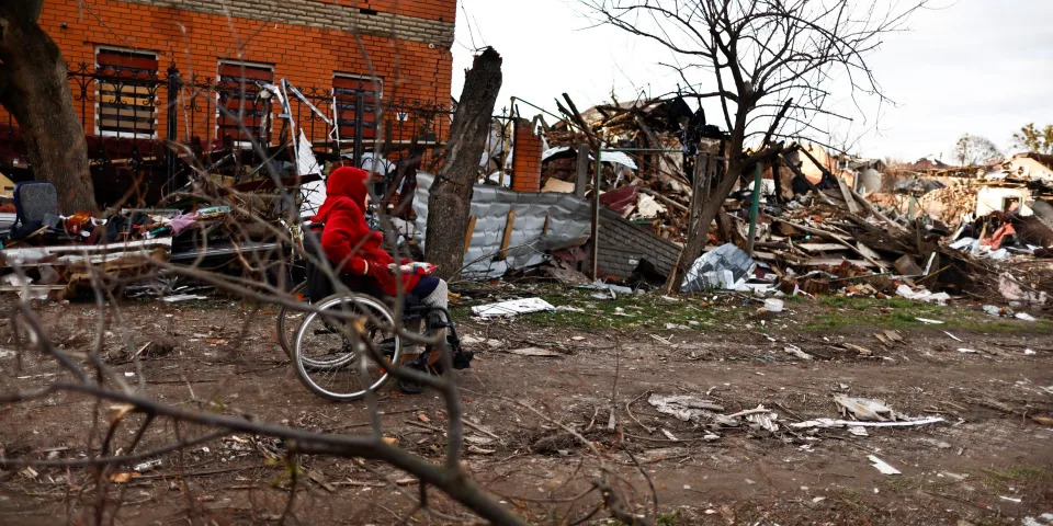 A woman sits on her wheelchair beside houses destroyed by Russian shelling amid Russia's invasion of Ukraine, in Sumy