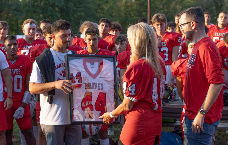 Regina Mullen receives a framed jersey honoring her late son, Kyle Mullen, during a pregame dedication ceremony retiring his Manalapan High School football number. Mullen died following Navy SEAL training in February 2022. Middletown South Football vs. Manalapan at Manalapan, NJ. on September 9, 2022.