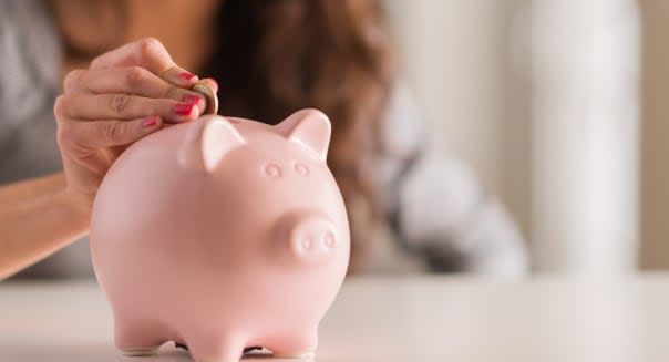 woman putting coin in piggy...