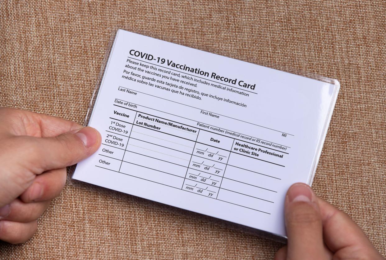 The laminated coronavirus vaccination card is held in the hands. The concept of defeating Covid-19 and keeping in safe copy of document. High quality photo