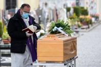 Un sacerdote, que lleva una mascarilla, consulta un libro de ritos funerarios mientras que le da su última bendición a un fallecido, en el exterior del cementerio de Bolgare, en Lombardía, Italia. (PIERO CRUCIATTI/AFP via Getty Images)