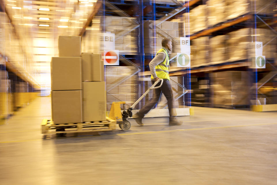 Worker carting boxes in warehouse