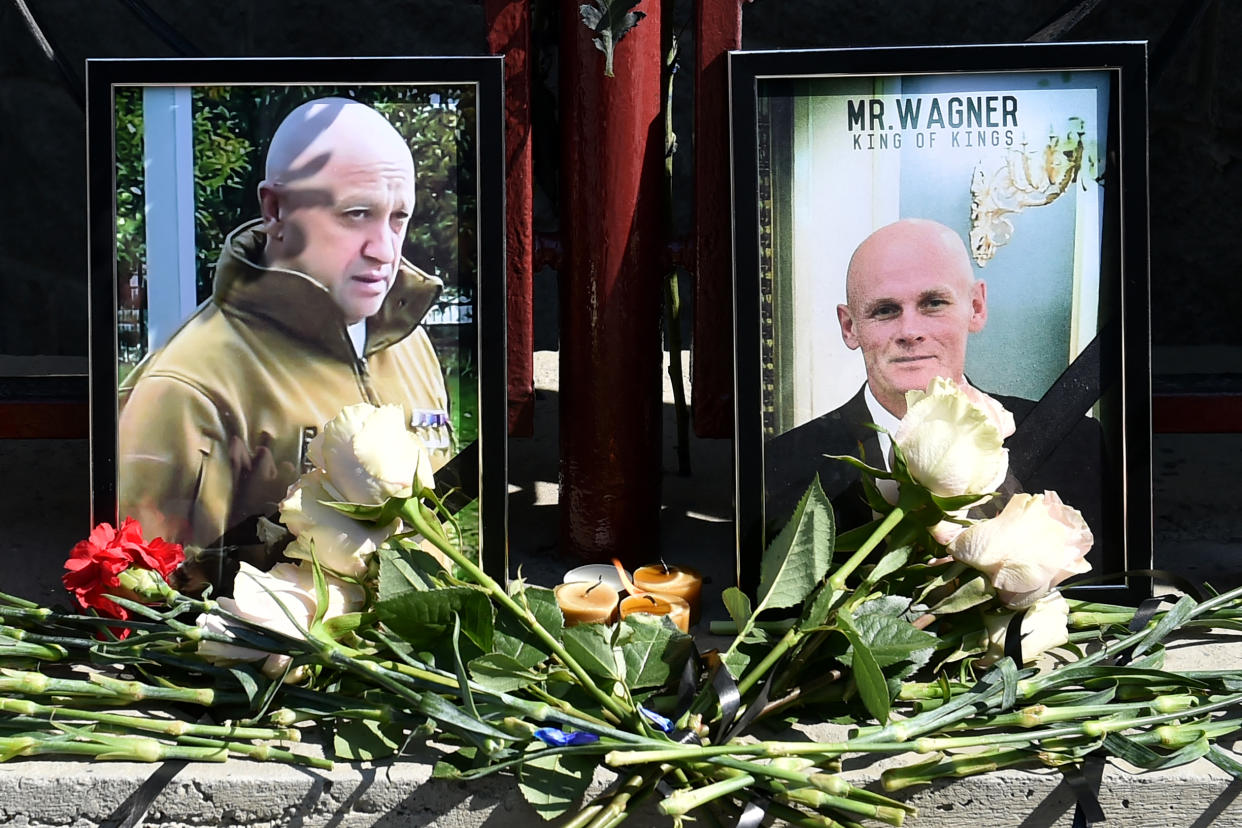 Portraits of Yevgeny Prigozhin and Dmitry Utkin, with flowers laid in front, are seen at a makeshift memorial.
