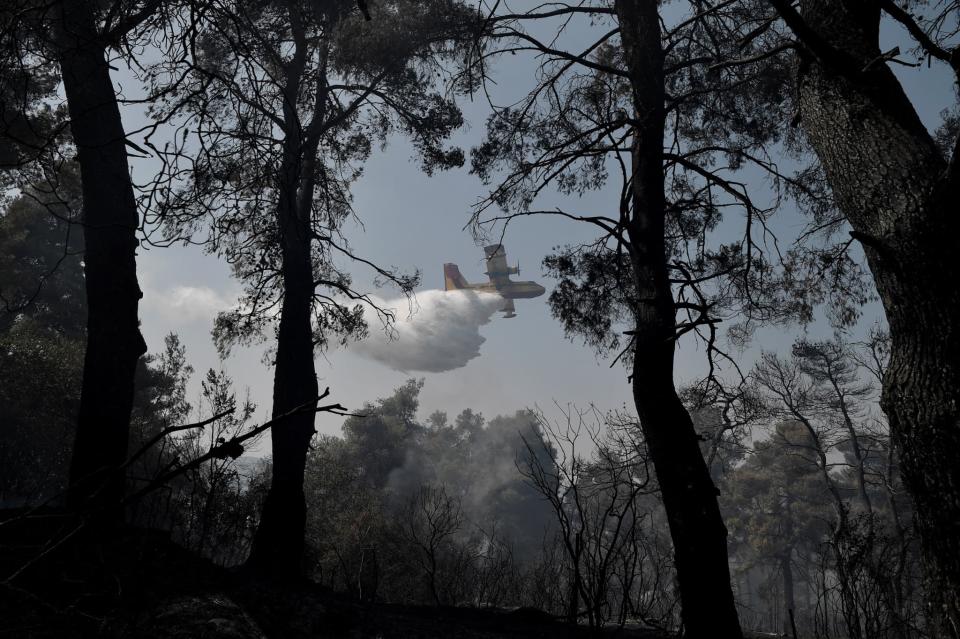 Un avion lâche de l'eau au-dessus d'un feu de forêt à Dionysos, au nord d'Athènes (Grèce), le 27 juillet 2021. - LOUISA GOULIAMAKI / AFP