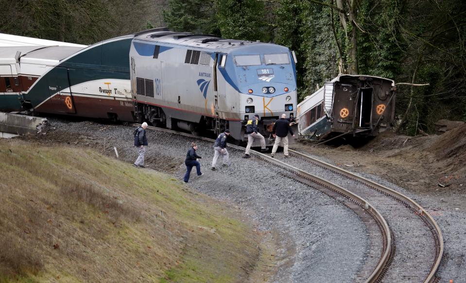 Police officials walk over tracks near a curve at the back of where an Amtrak train derailed above Interstate 5, in DuPont, Wash — Shutterstock/AP