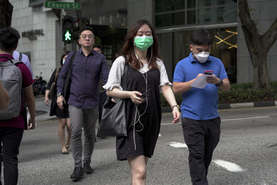 SINGAPORE, SINGAPORE - FEBRUARY 28: People wearing masks cross a traffic junction at the Central Business District on February 28, 2020 in Singapore. The coronavirus, originating in Wuhan, China has spread to over 80,000 people globally, more than 50 countries have now been infected.  (Photo by Ore Huiying/Getty Images)