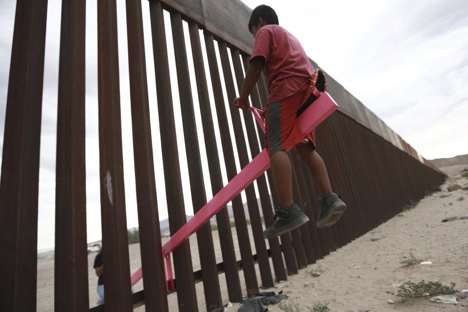 CORRECTS THE FIRST NAME OF THE PROFESSOR TO RONALD, NOT RONALDO AND THE LAST NAME OF THE PHOTOGRAPHER TO CHAVEZ, NOT TORRES - A child plays seesaw installed between the border fence that divides Mexico from the United States in Ciudad de Juarez, Mexico, Sunday, July 28, 2019. The seesaw was designed by Ronald Rael, a professor of architecture in California. (AP Photo/Christian Chavez)