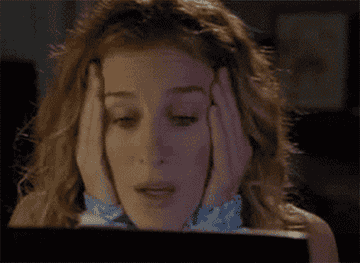 Carrie Bradshaw makes a distraught face while looking at her laptop